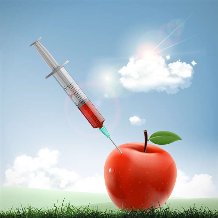 Imagem de uma seringa com um líquido vermelho preso em uma maçã
